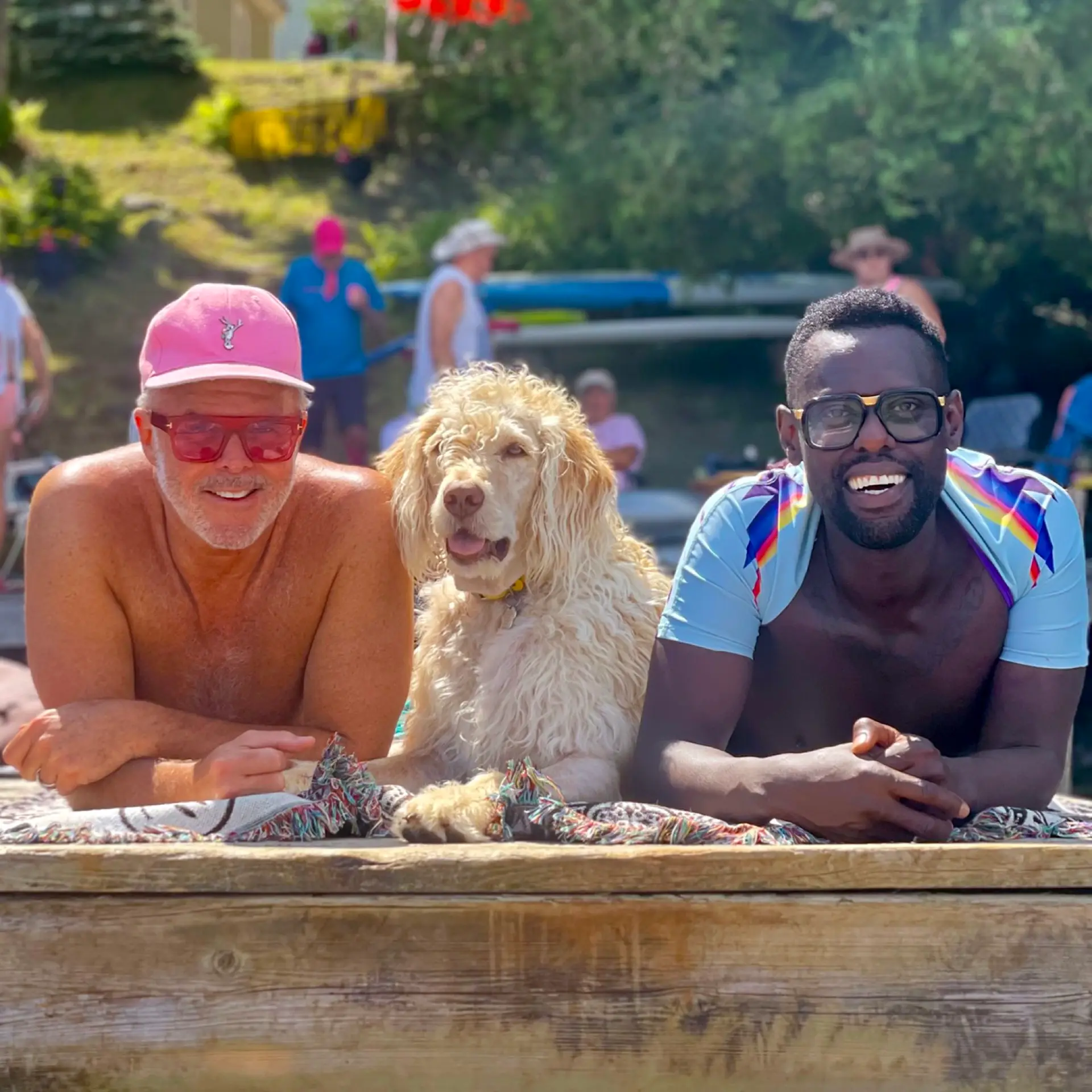 Barr Gilmore in a pink cap, a curly-coated dog, and Pierre Antoine Alexandre cooling off at the lake with swimmers behind them